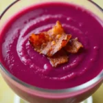 Bol de soupe aux choux rouges fumante sur une table en bois.