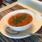 Bol de soupe tomate vermicelle sur une table en bois